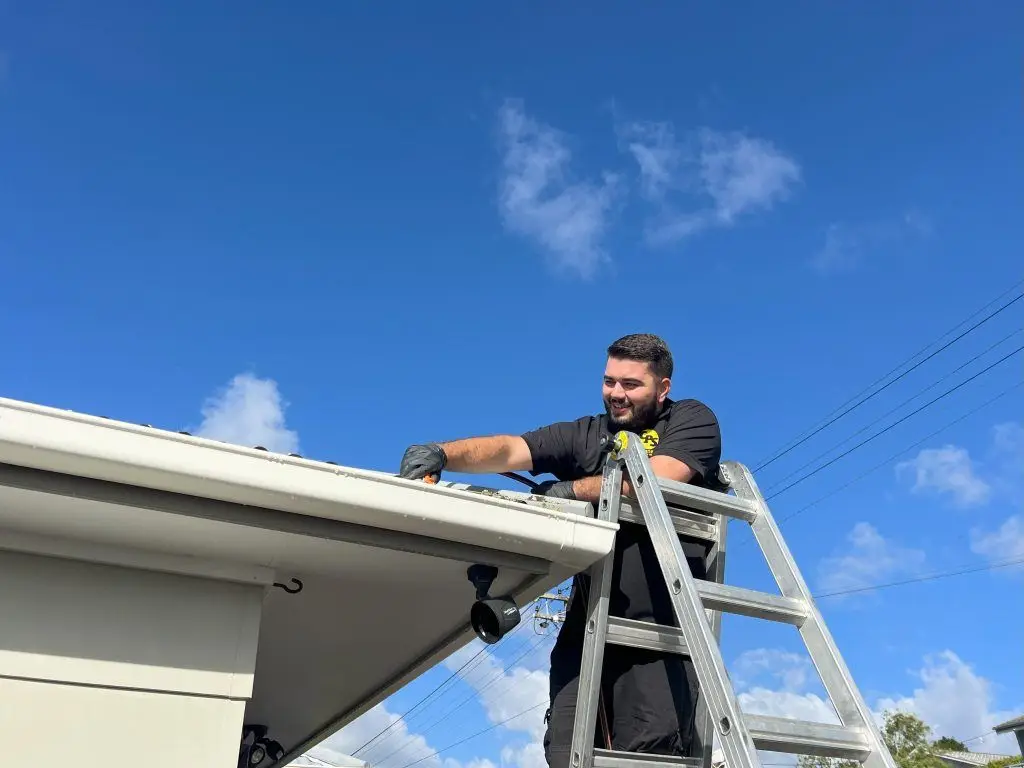 Connect Property Services worker cleaning gutters at a residential property in Glenfield, North Shore, removing leaves, moss, and debris to ensure proper drainage and prevent water damage.